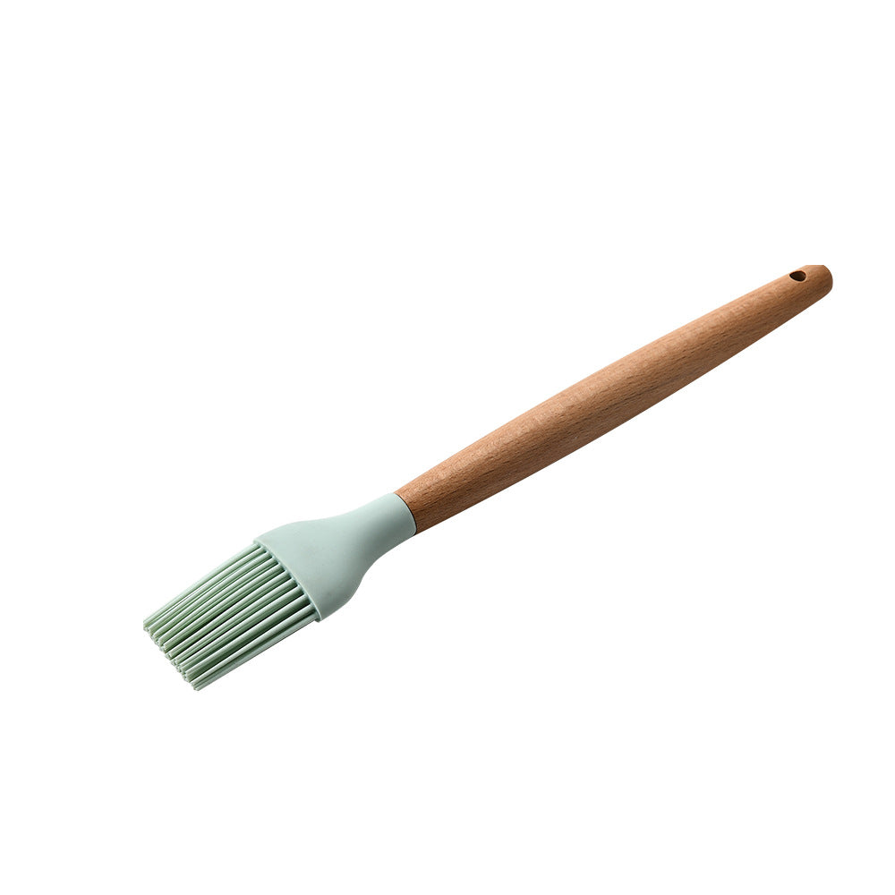 Basting brush with green silicone head and wooden handle on a white background