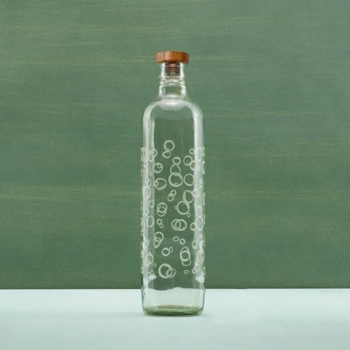 Clear glass bottle with bubble design on a green background