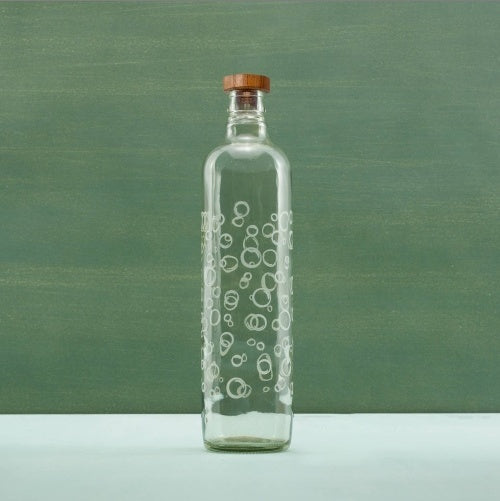 Clear glass bottle with bubble pattern on a green background