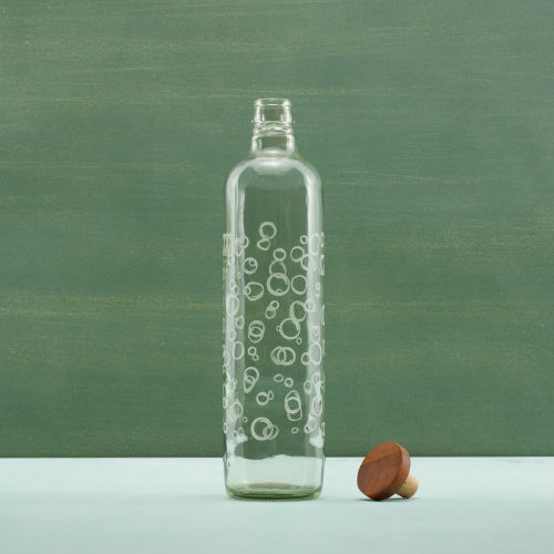 Clear glass bottle with bubble pattern on a green background