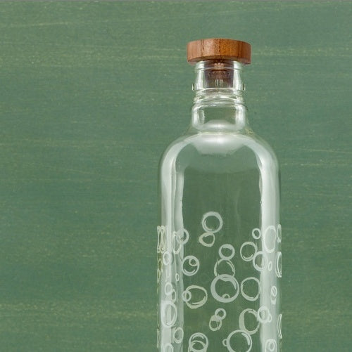 Clear glass bottle with wooden cap on a green background