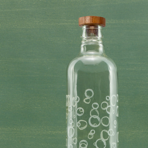 Clear glass bottle with wooden cap on a green background