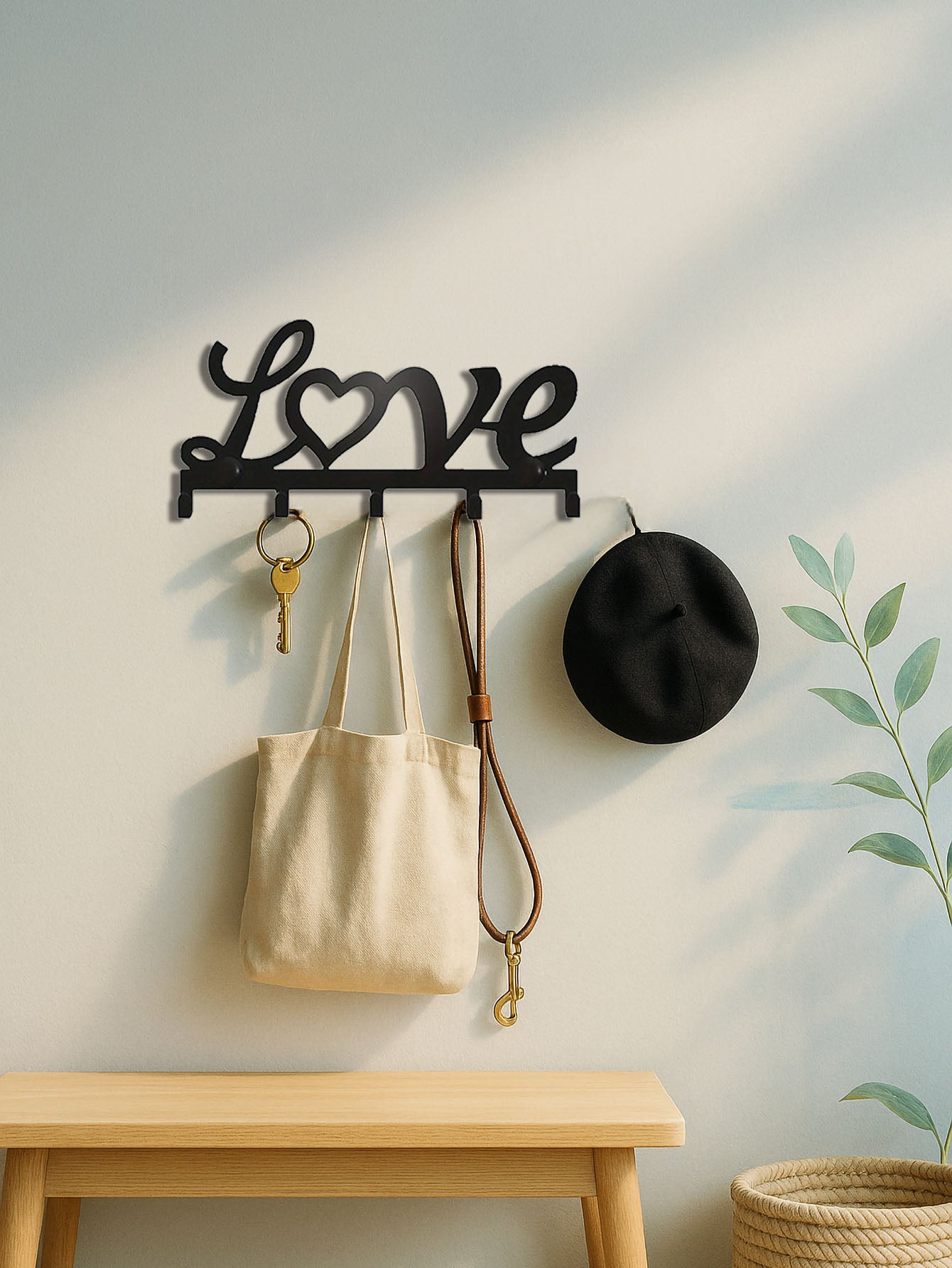 Decorative wall hook with 'love' design holding a bag, key, and hat against a light wall.