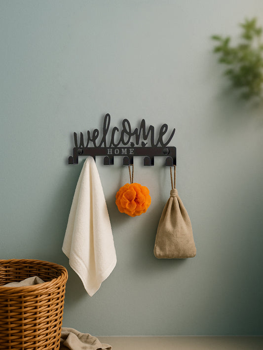 Decorative wall hook with 'welcome home' text on a light green wall with a basket and items below.
