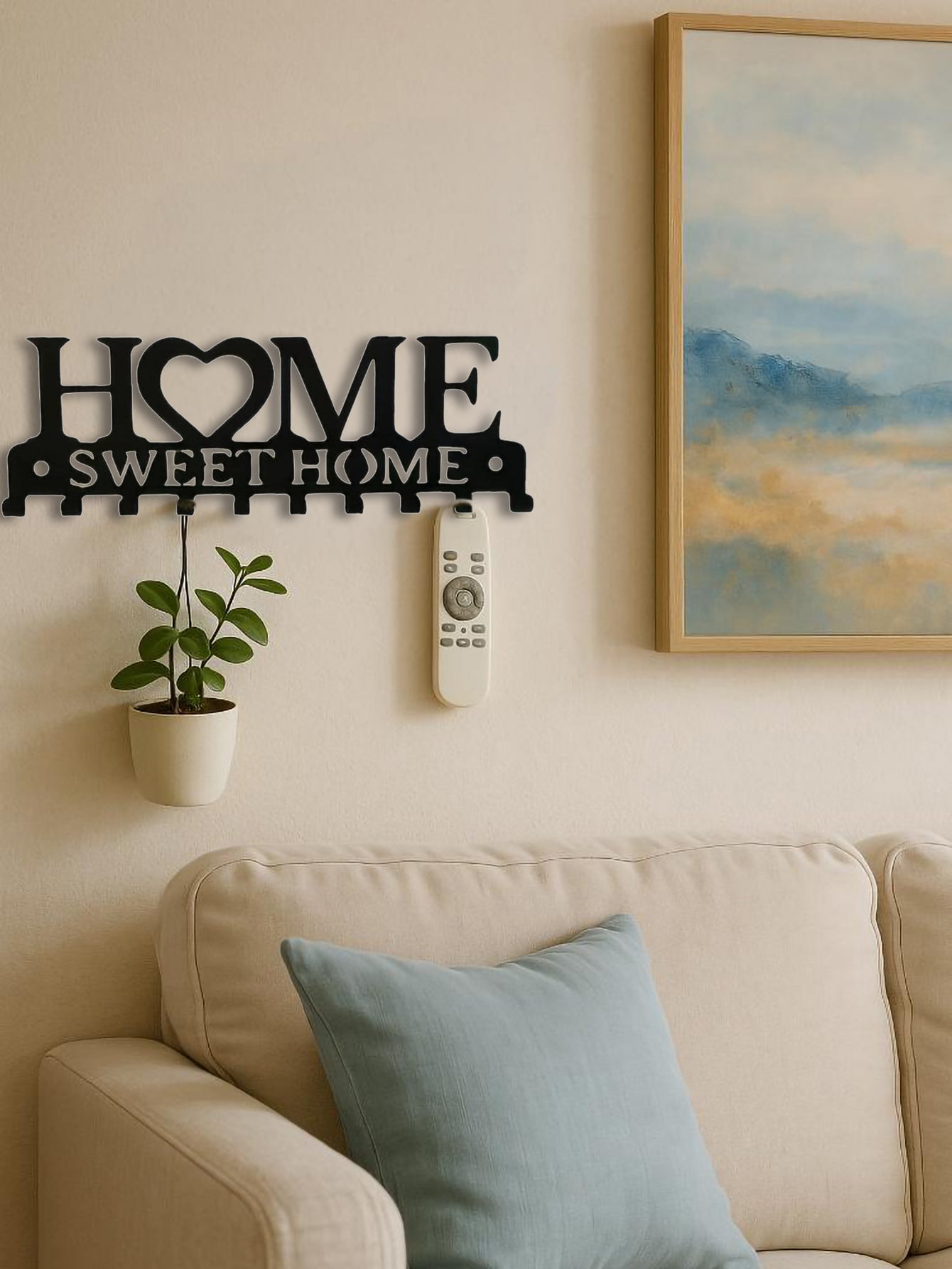 Decorative wall sign 'Home Sweet Home' on a wall with a couch and painting in the background.