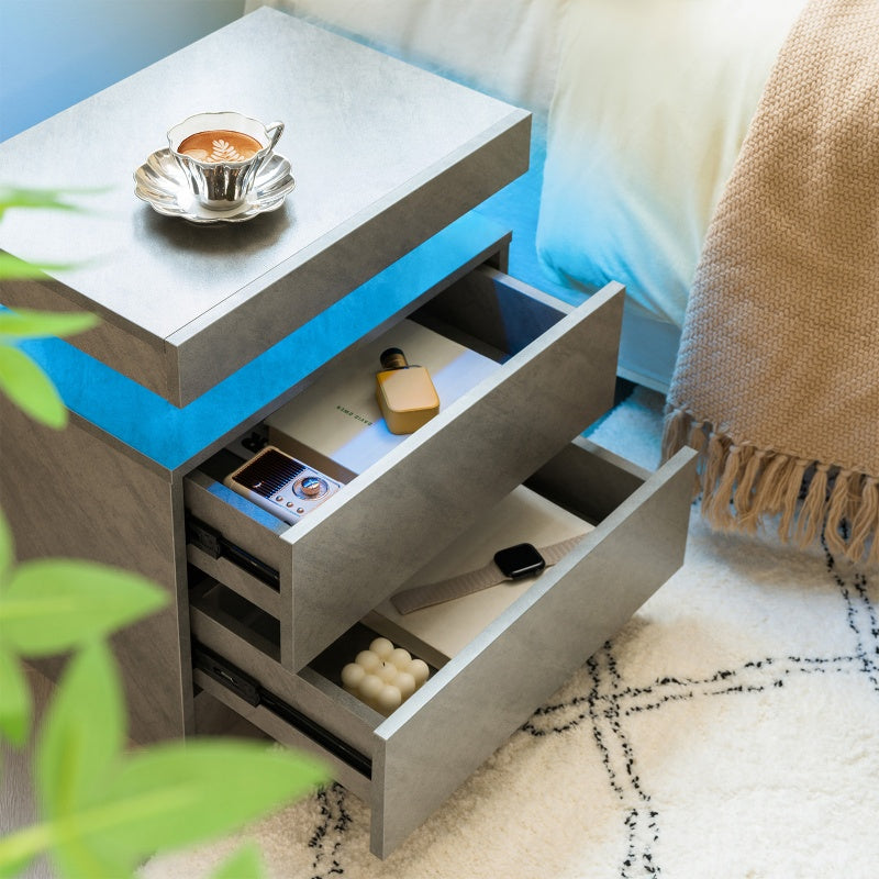 Modern nightstand with open drawer, cup of coffee, and phone on a cozy bedroom setting.