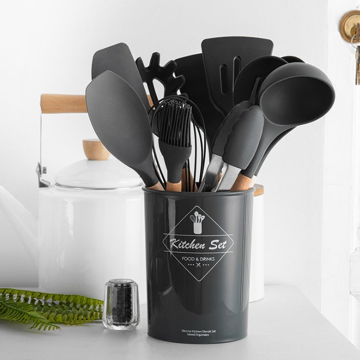 Set of black kitchen utensils in a holder on a white surface